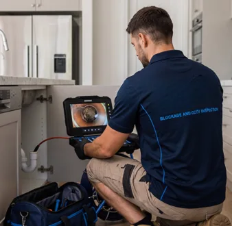 Plumber clearing a blocked toilet in a St Andrews bathroom